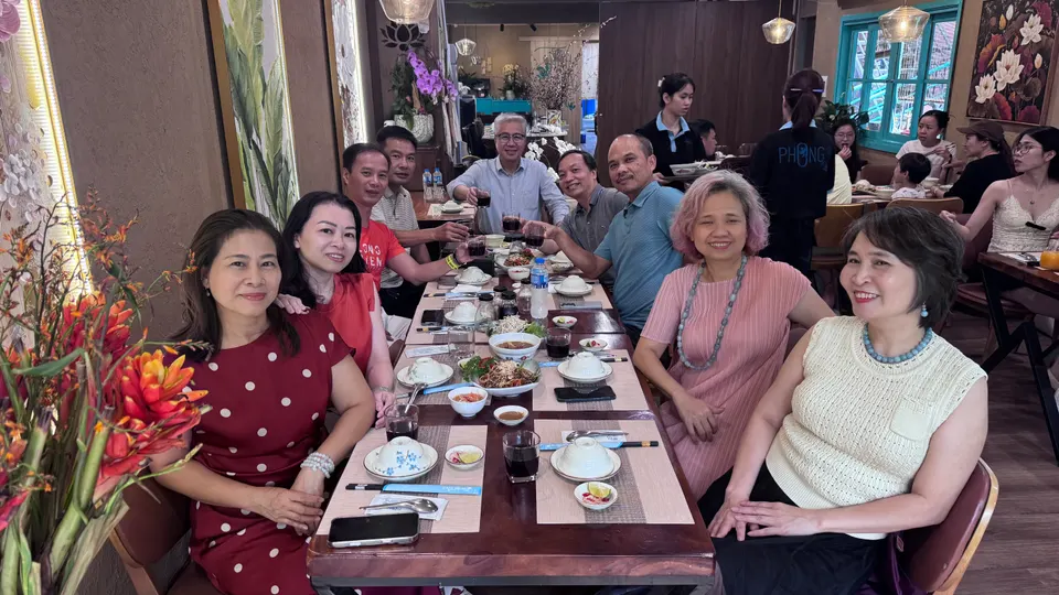 Các bố mẹ Lớp Chúng Mình ngồi quanh bàn dài trong nhà hàng, mỉm cười nhìn ống kính
